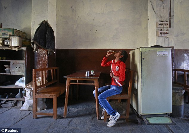 New struggle: During his struggle to find work Gopal Kishan, 16, drinks liquor at a roadside restaurant on the outskirts of his village near Baran