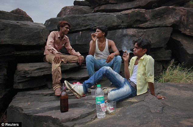 Escape: Helping occupy some time, the young father smokes a cigarette while drinking with his friends on the outskirts of their village